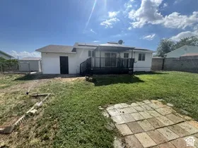 Expansive green space featuring a wood deck, paved patio, and a separate storage shed