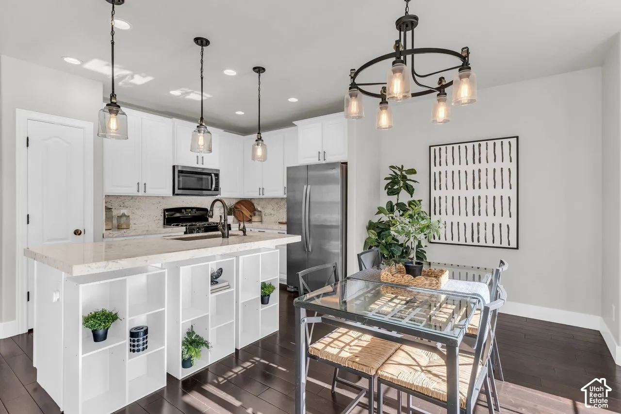 Kitchen and dining with updated light fixtures and hardwood floors. The sellers placed shelving units below the bar on the island, but those can easily be removed to accommodate barstools