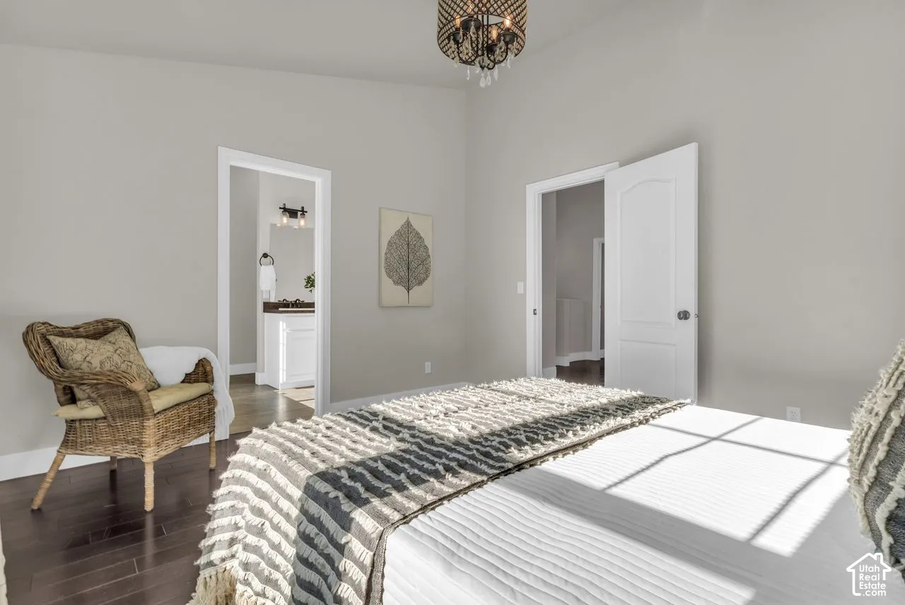Spacious primary bedroom with updated light fixture, vaulted ceilings, and hardwood flooring