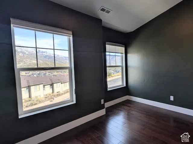 Secondary bedroom with hardwood floors, vaulted ceiling, and mountain views