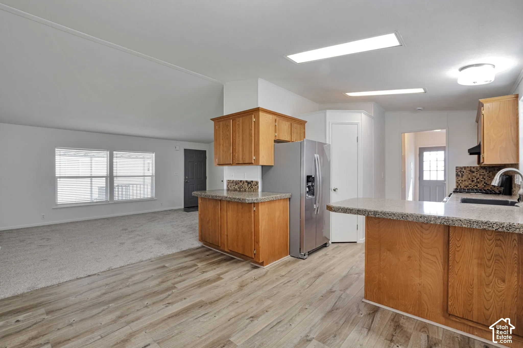 Wood-finish flooring, light wood cabinetry, stone-finish countertops, stainless steel appliance, and recessed lighting