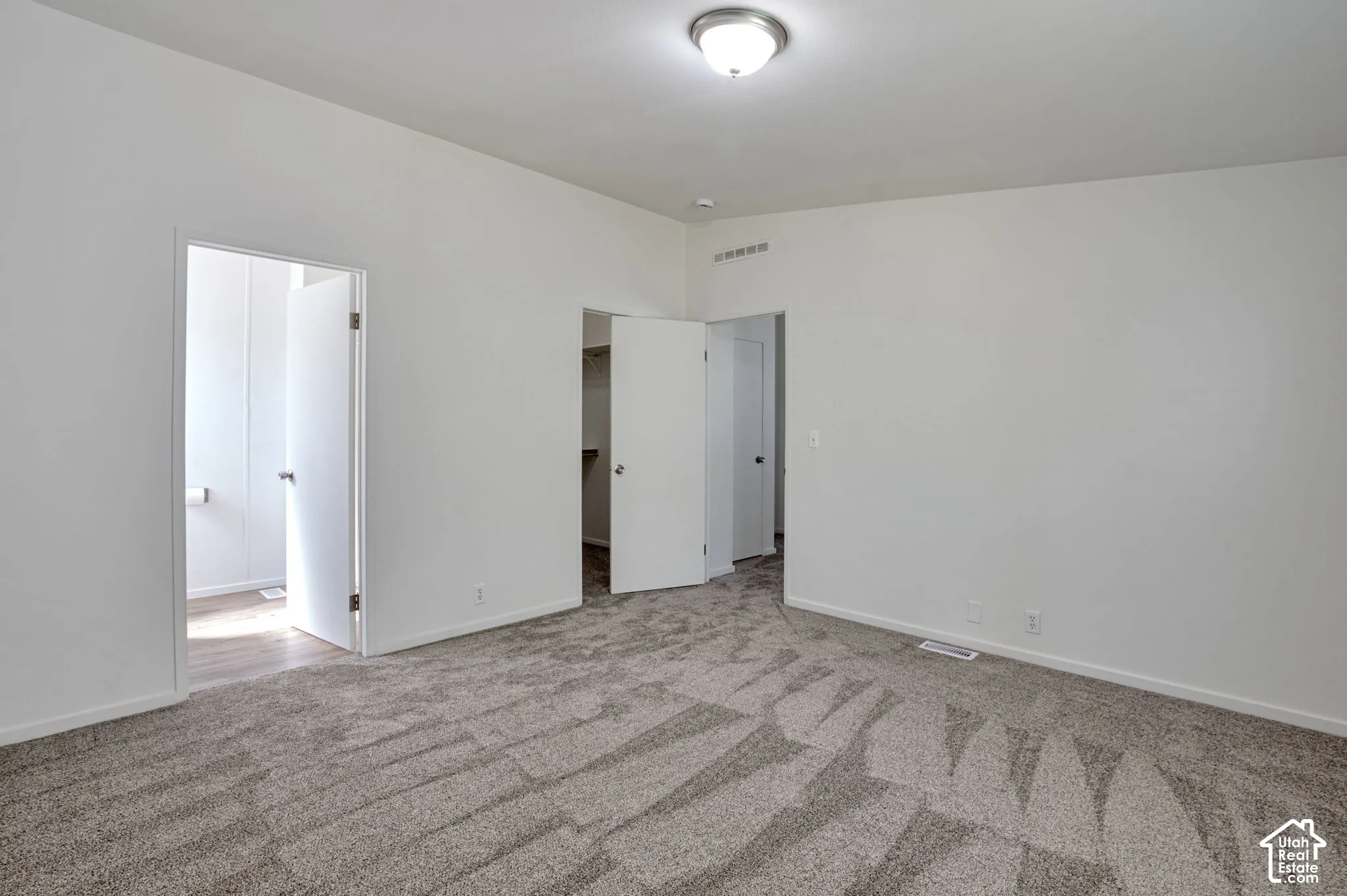 Neutral wall colors, patterned carpet flooring, flush mount ceiling light fixture, and white interior doors
