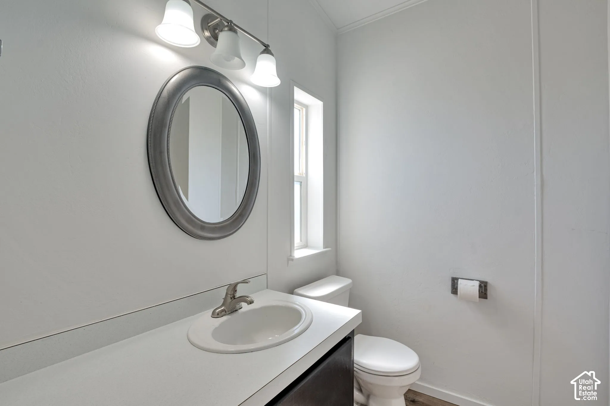 Vanity with integrated sink, brushed nickel faucet, oval mirror, and three-light fixture