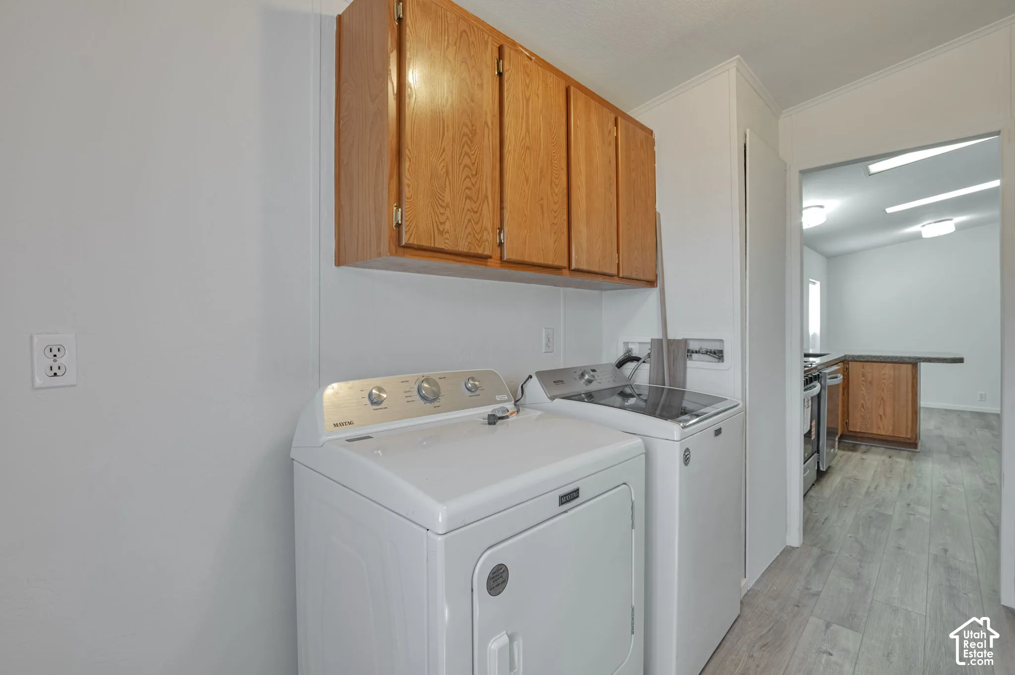 Laundry area featuring wood-finish cabinetry and light wood-finish flooring