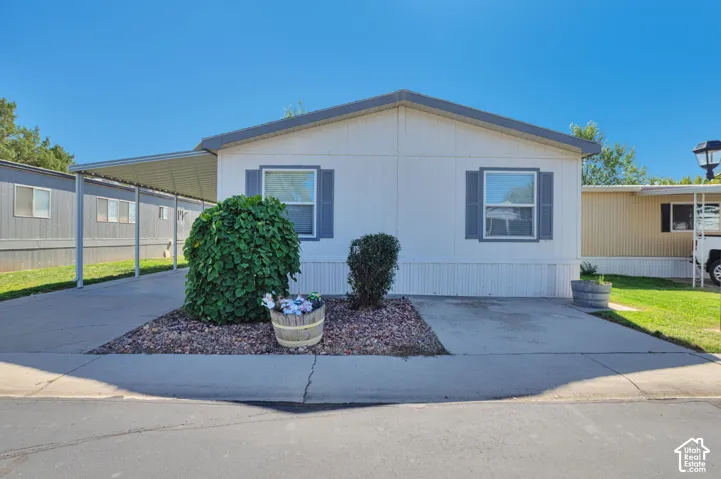 White siding exterior with a carport, concrete driveway, and gray window shutters