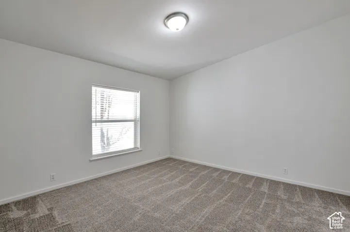 Neutral paint palette with textured carpet flooring, a single window with blinds, and a flush-mount ceiling light fixture