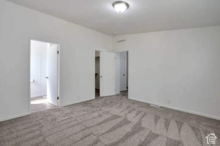 Neutral wall colors, patterned carpet flooring, flush mount ceiling light fixture, and white interior doors