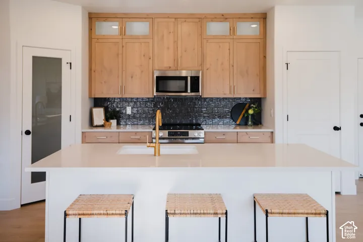 Kitchen featuring a large center island with an integrated sink and gold-finish faucet