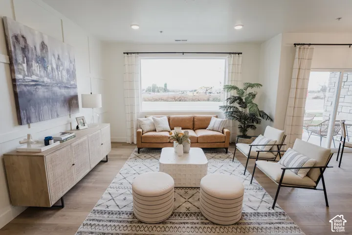 Open-concept living area featuring wood-finish flooring, a large picture window, recessed lighting, and a sliding glass door to the exterior