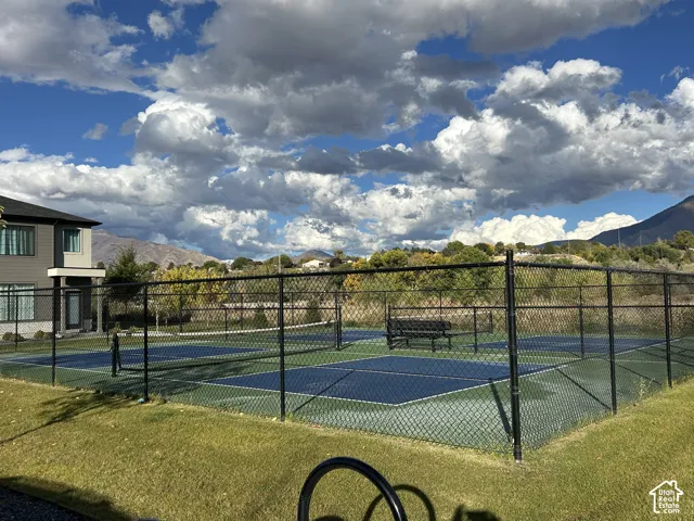 Outdoor multi-sport court with chain-link fencing, featuring a bench and paved surface