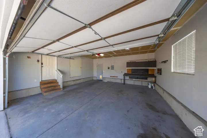 Attached two-car garage featuring a concrete floor, built-in workbench, and a white window with blinds