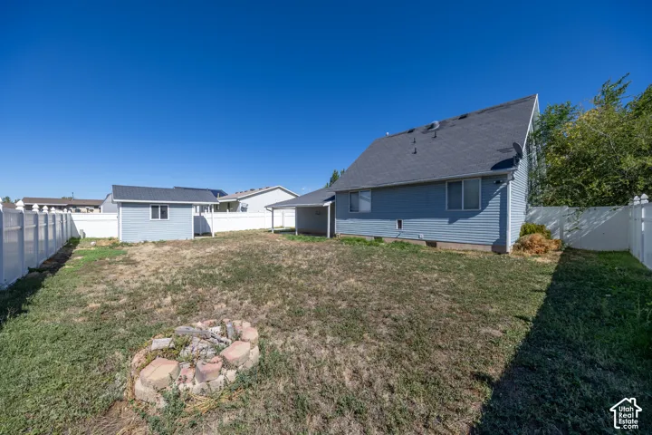 Expansive backyard with a dedicated fire pit area, fully enclosed by a white privacy fence
