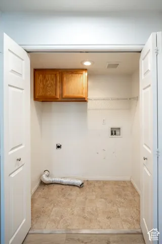 Main floor laundry. Built-in overhead cabinetry, recessed ceiling lighting, wire shelving, and neutral tone flooring.