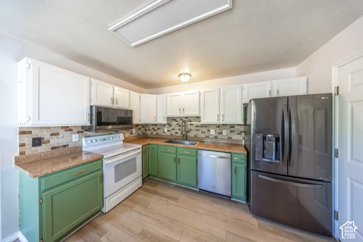 Kitchen featuring wood-finish flooring, two-tone cabinetry, tiled backsplash, and stainless steel appliances. (included)