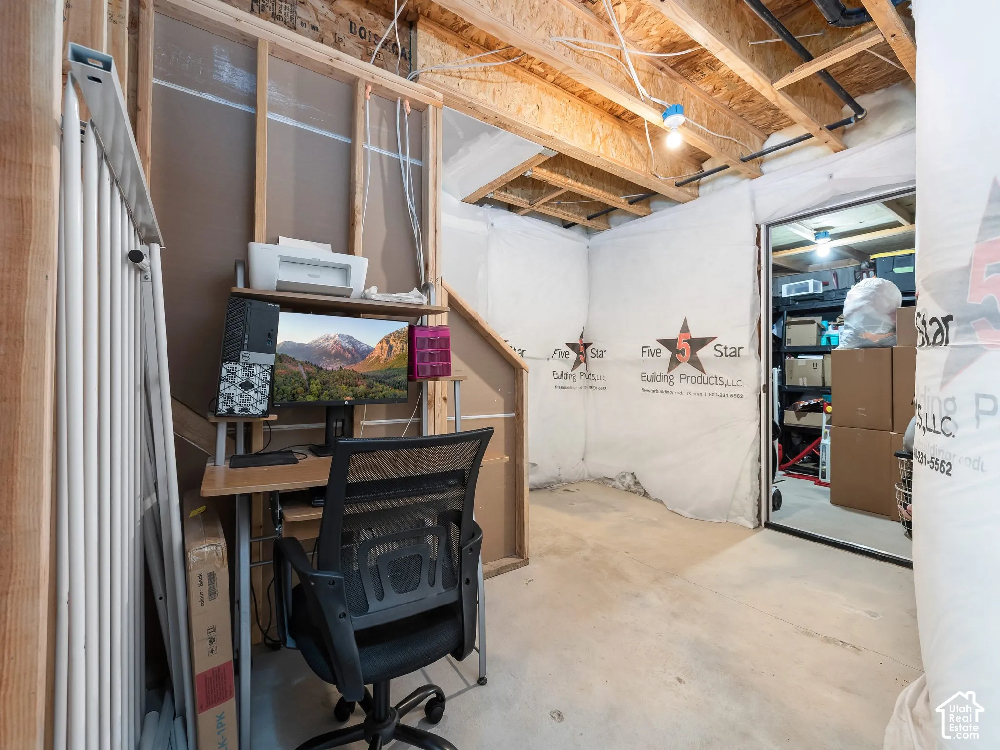 Unfinished basement with exposed ceiling joists, concrete flooring, and framed wall structure