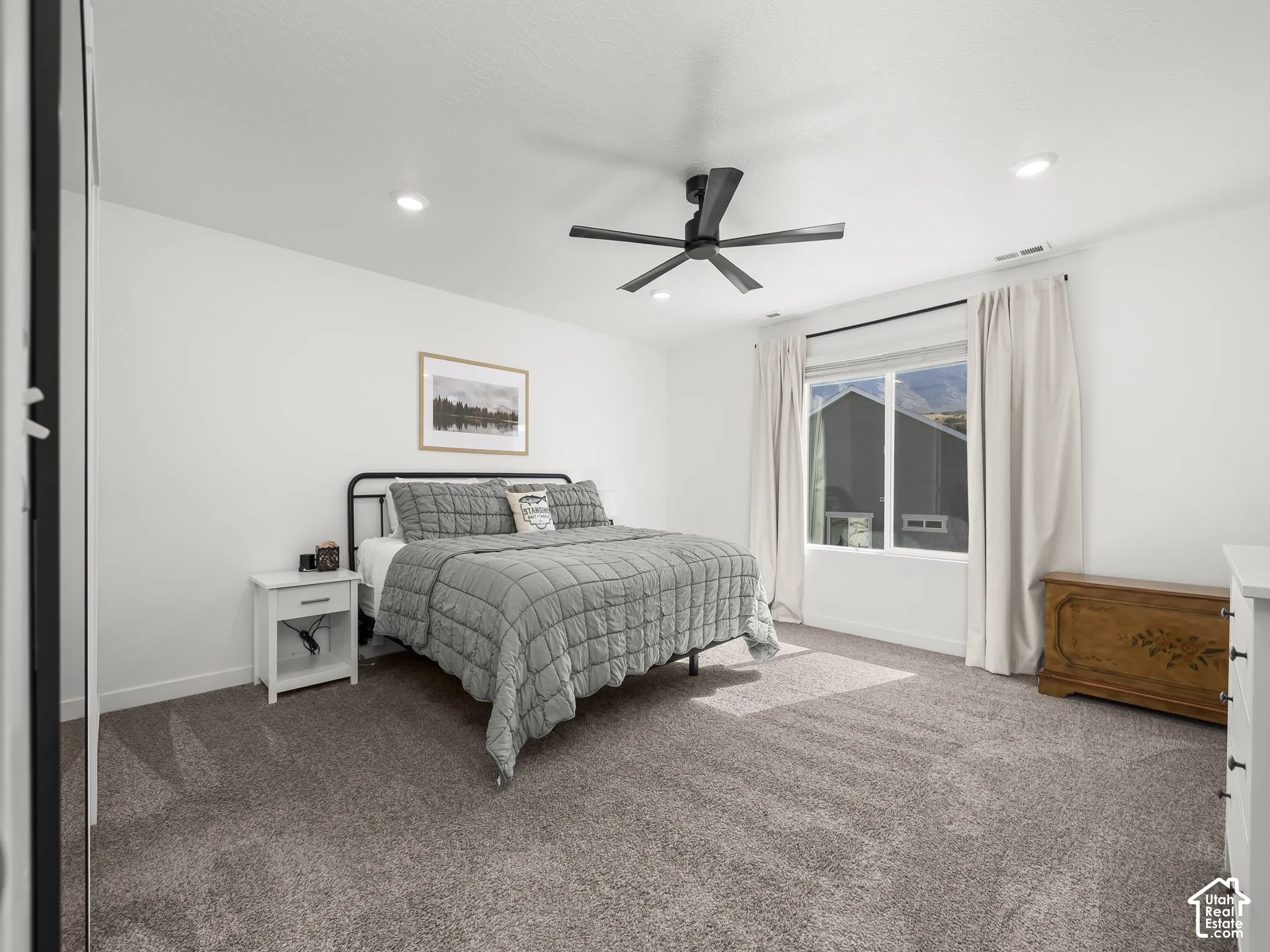 Plush carpeting, recessed ceiling lighting, a modern ceiling fan, and a large window with mountain scenery