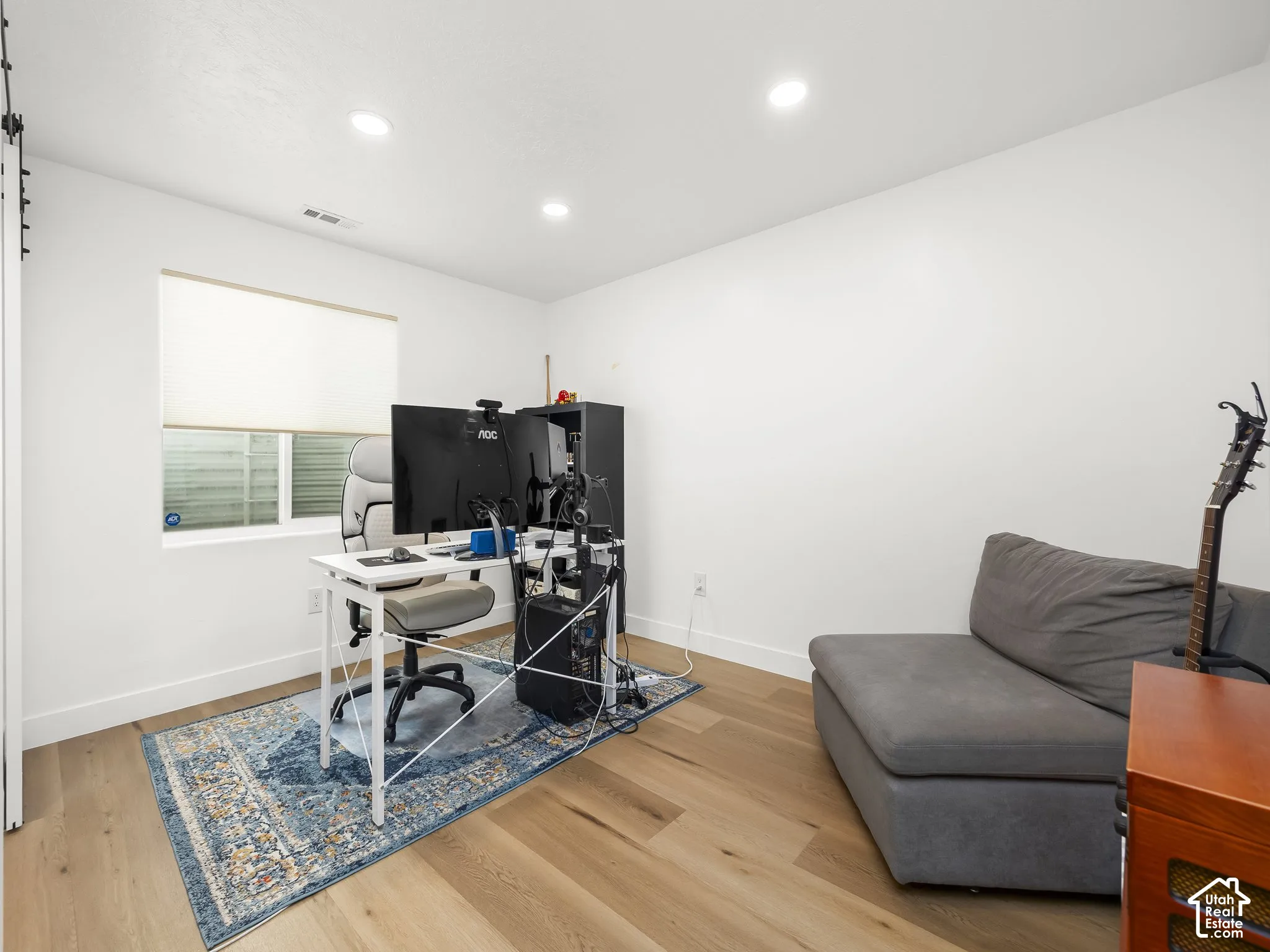 Recessed ceiling lighting, hard-surface flooring, white walls, and a window with blinds