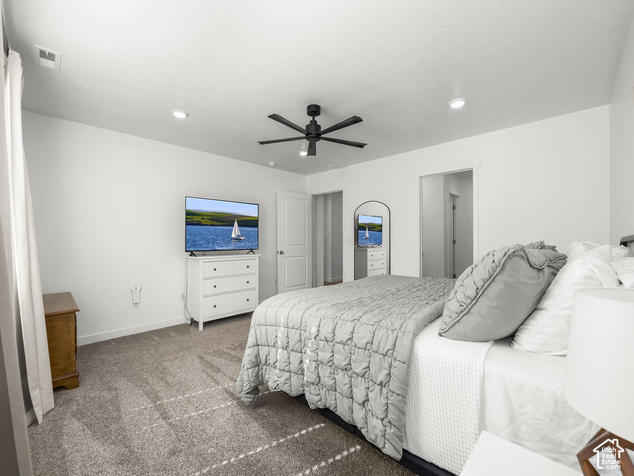Recessed ceiling lighting, ceiling fan, neutral wall color, and gray carpeting