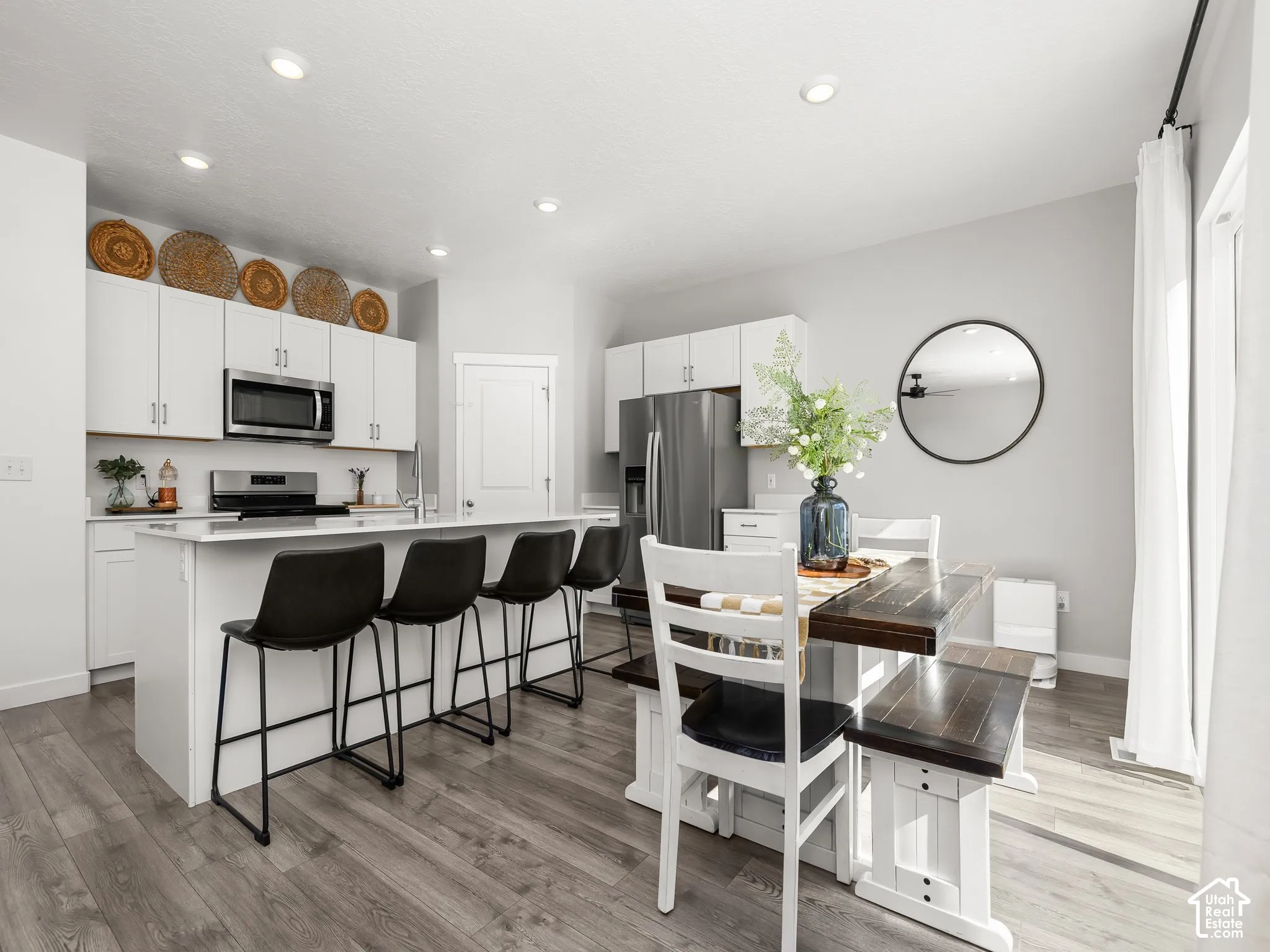 Open-concept kitchen and dining area featuring recessed lighting, white cabinetry, stainless steel appliances, a kitchen island, and wood-finish flooring