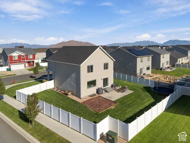 Expansive backyard featuring a manicured lawn, white privacy fencing, and a concrete patio