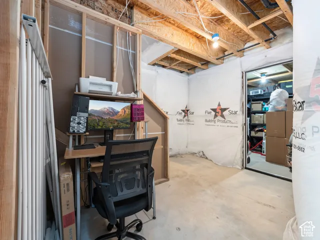 Unfinished basement with exposed ceiling joists, concrete flooring, and framed wall structure