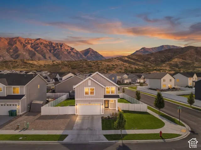 Modern construction with a two-car garage, white fencing, and a manicured lawn