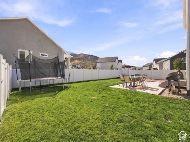 Expansive green lawn with a concrete patio, privacy fencing, and distant mountain scenery