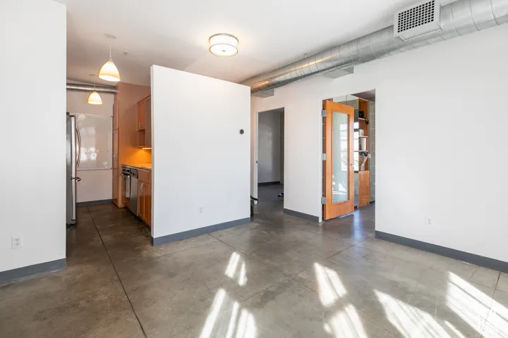 Open-concept living space featuring polished concrete flooring, white walls with blue base trim, and abundant natural light from large windows