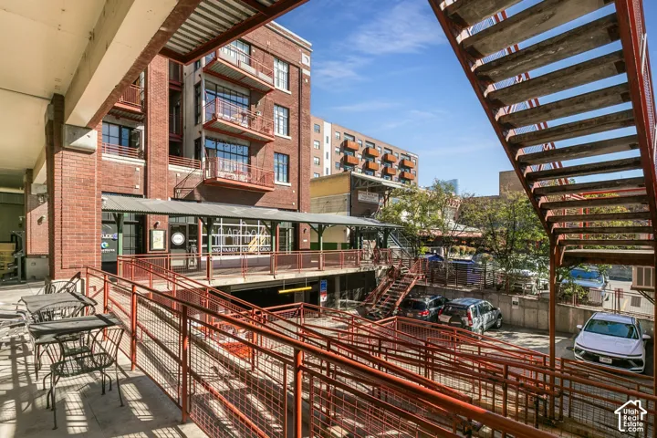 Brick building exterior featuring multiple balconies, ground-level commercial space, and a dedicated entry ramp