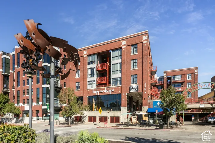 Brick facade building with large storefront windows, multiple levels of balconies, and a street-level commercial presence