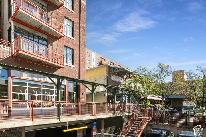 Brick-clad building with multiple levels of balconies, large windows, and a ground-level commercial space