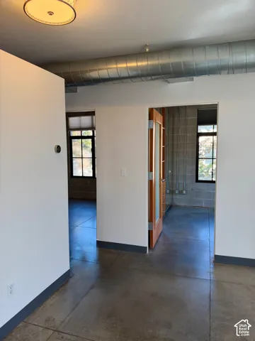 Exposed ductwork, durable concrete flooring, and an interior wood-frame door with frosted glass panels