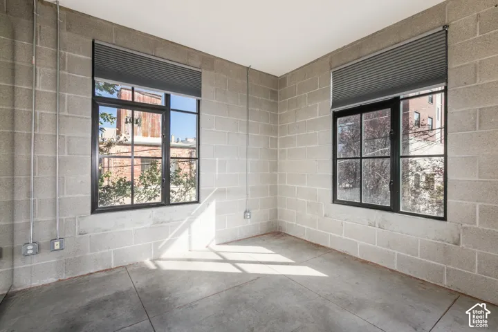 Concrete block walls, exposed conduit, industrial-style windows, concrete flooring, and window treatments