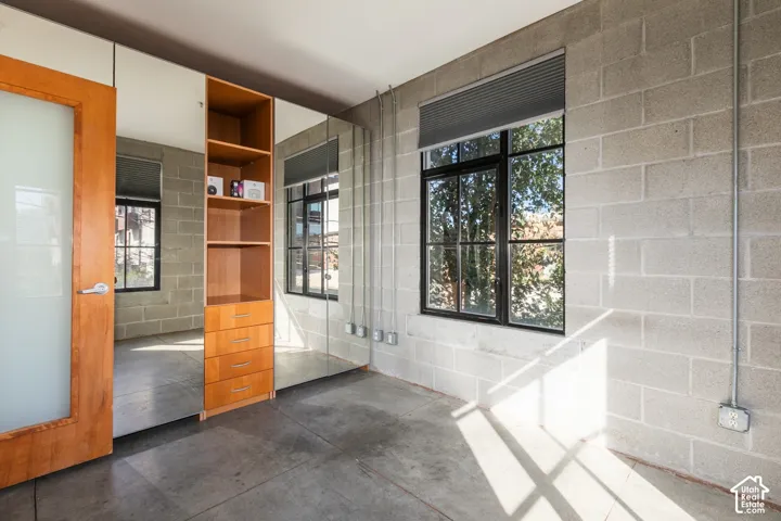 Polished concrete flooring, exposed concrete block walls, and large black-framed windows with blinds