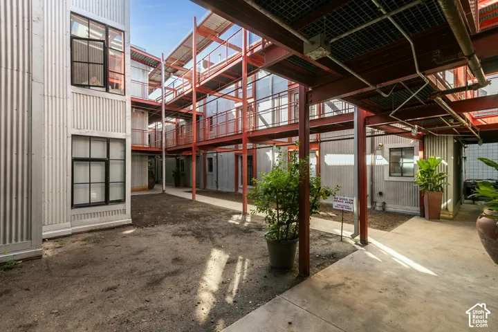 Corrugated metal siding, exposed red structural beams, concrete pathways, and multi-level walkways