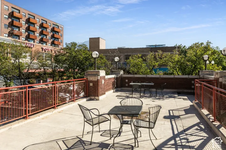 Expansive rooftop patio with concrete flooring, brick privacy walls, and a metal railing system