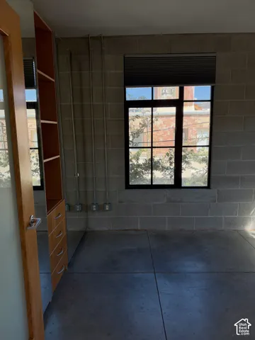 Exposed concrete block walls, industrial-style window, built-in shelving, integrated drawers, and polished concrete flooring