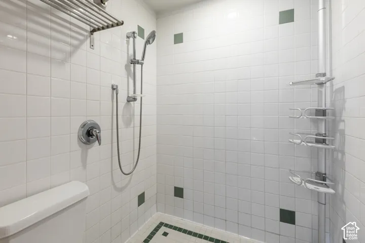 White tiled shower enclosure with chrome fixtures and integrated shelving