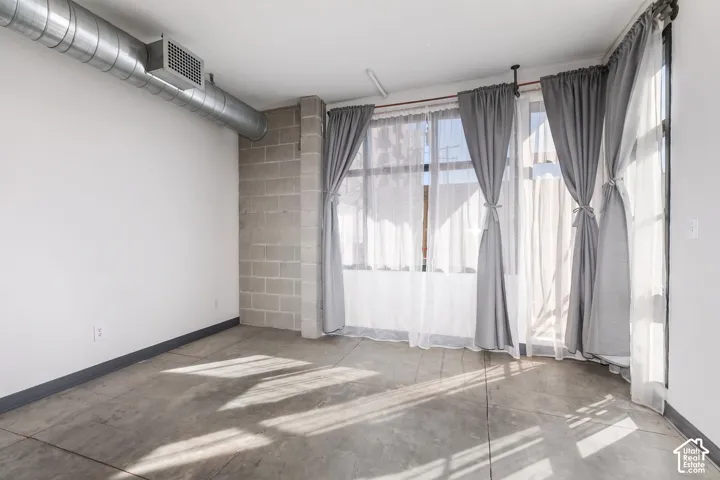 Polished concrete flooring, exposed spiral ductwork, large windows, and a concrete block column