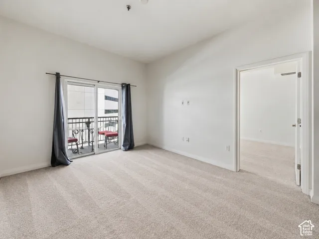 Spacious Living Area with brand-new neutral carpet flooring, large sliding glass door with blackout curtains opening to a private balcony.
