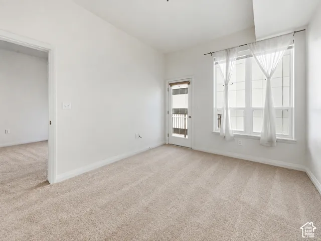 Brand New neutral toned carpeting, white painted walls, large window with white framing, white door with glass panel, and white trim