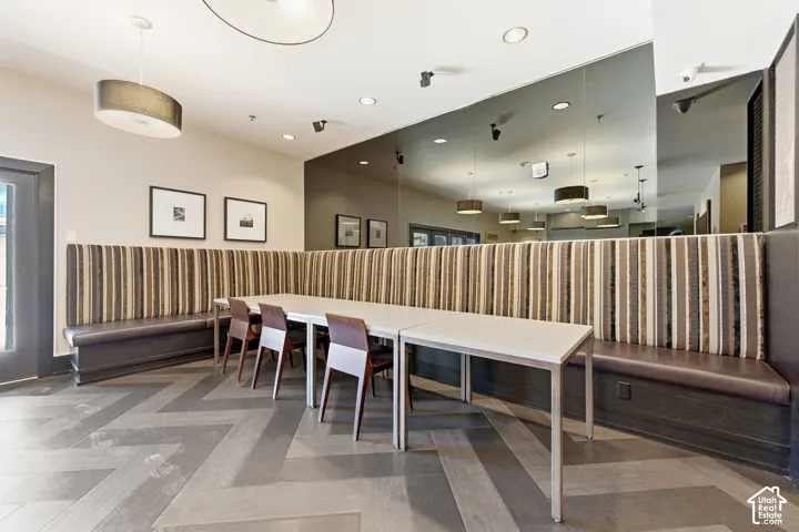 Spacious Owner lounge Herringbone pattern wood-finish flooring, built-in upholstered banquet seating, recessed lighting, and modern pendant light fixtures