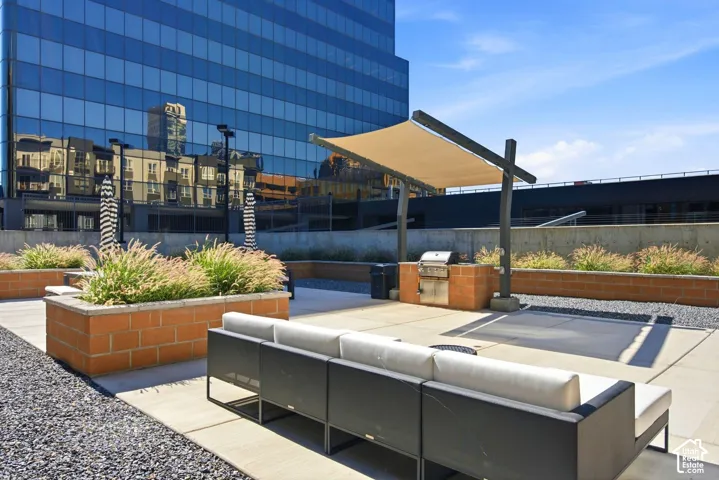 Rooftop Owner patio with built-in planters featuring mature greenery, a shaded grilling station, and decorative gravel accents