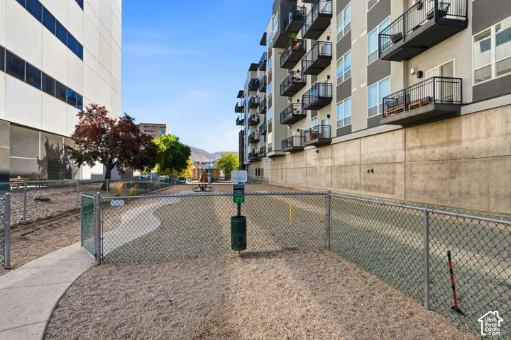 Gated outdoor Dog Run area featuring a gravel surface, chain-link fencing, and a pet waste station