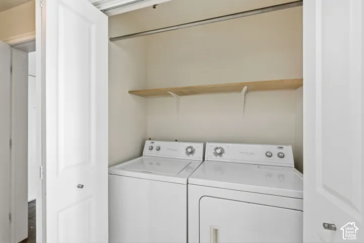 Dedicated laundry closet with bi-fold doors, white washer and dryer, and built-in shelving