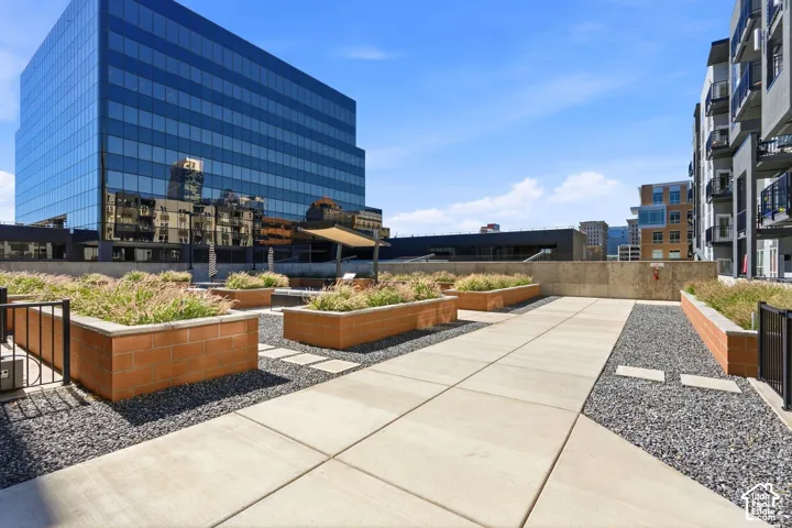 Rooftop patio featuring concrete paver pathways, decorative gravel, and brick planters with established greenery