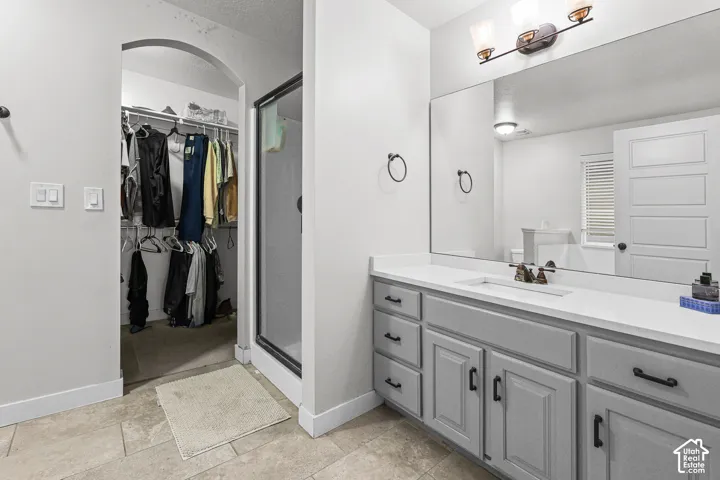Tiled flooring, double vanity with white countertop, recessed lighting, and an arched entryway
