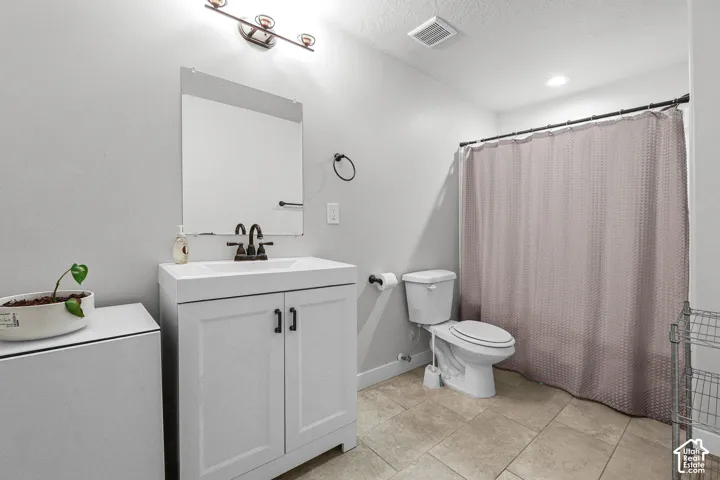 White vanity with integrated sink, bronze-finish faucet, framed mirror, and tiled flooring