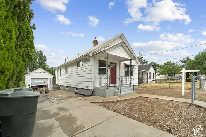 White siding exterior with a red front door, covered porch, and concrete front steps