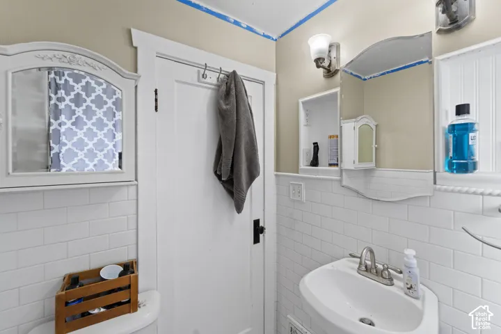 White subway tile wainscoting, recessed wall shelving, wall-mounted mirror, and a wall-mounted light fixture